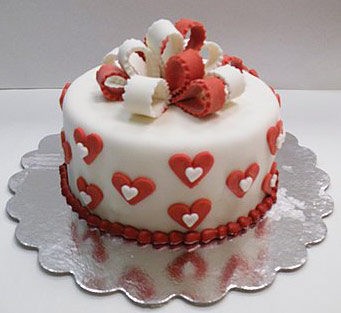 Festive Love Cake, white hearts on red hearts on white cake with red and white bow